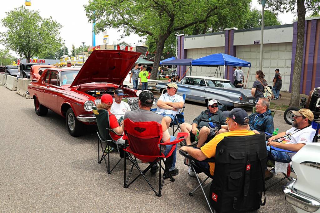 Group of men and women sitting next to a classic car at MSRA Back to the 50s