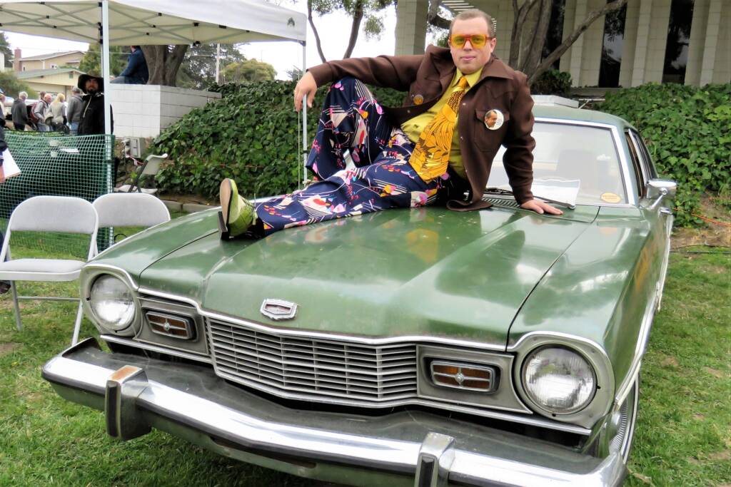 Man sitting on top of classic green car at the Concours d'Lemons