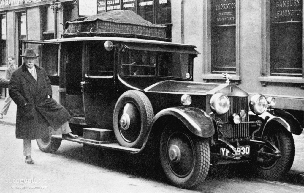 Black and white photo of an original Rolls-Royce Phantom I with man standing next to it