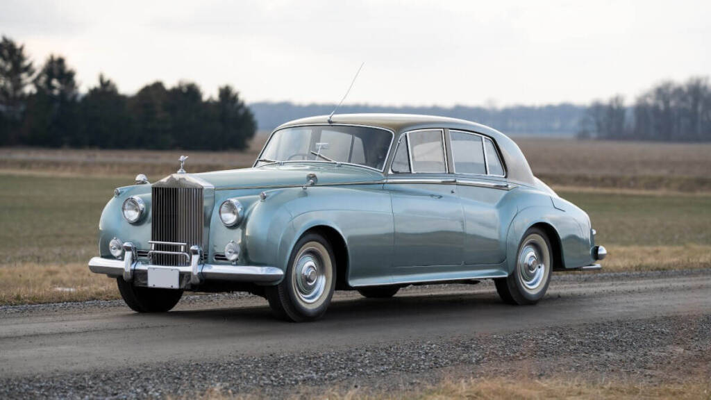 Blue classic Rolls-Royce Silver Cloud parked on a dirt road in a small town