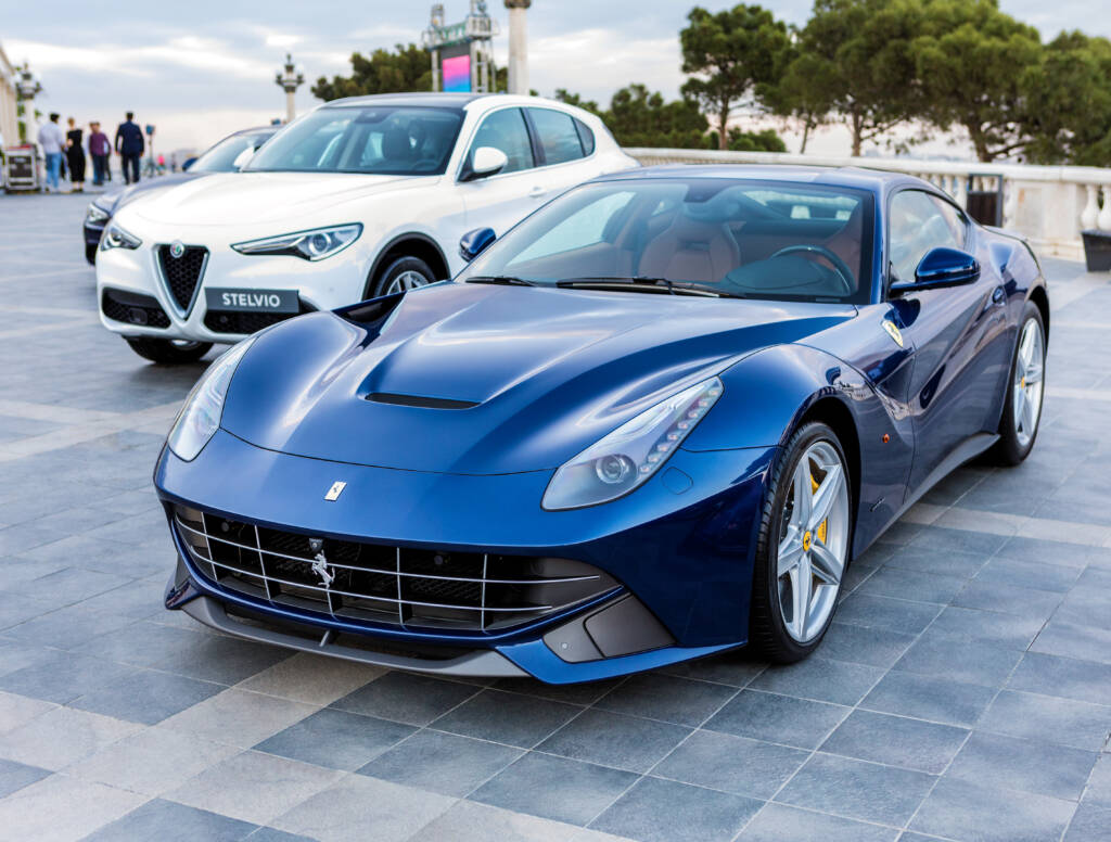 Ferrari F12berlinetta in blue next to an Alfa Romeo in the city