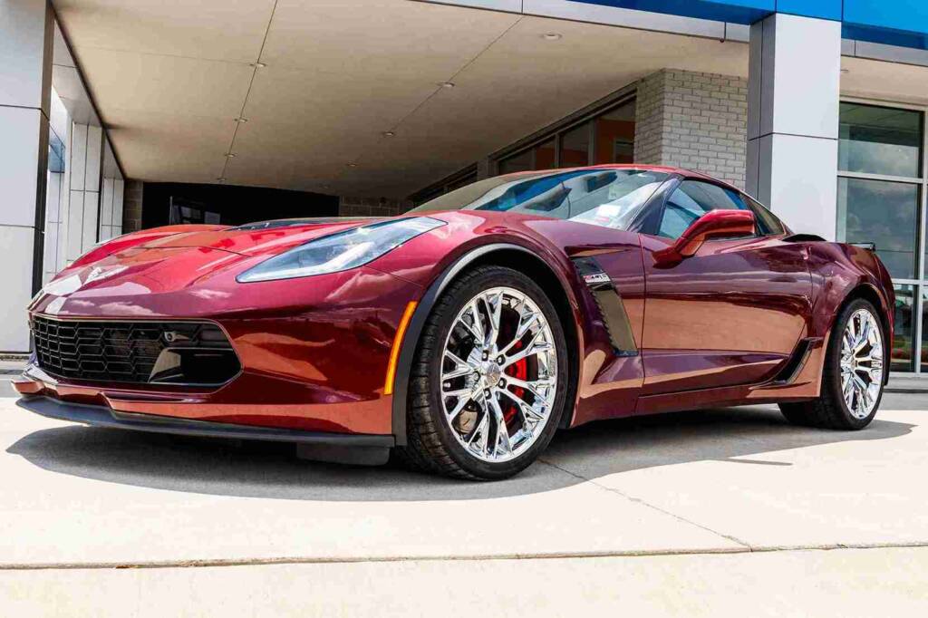 Cherry red Corvette parked outside of a Chevrolet dealership