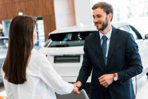 Car salesman shaking hands after a woman buys car