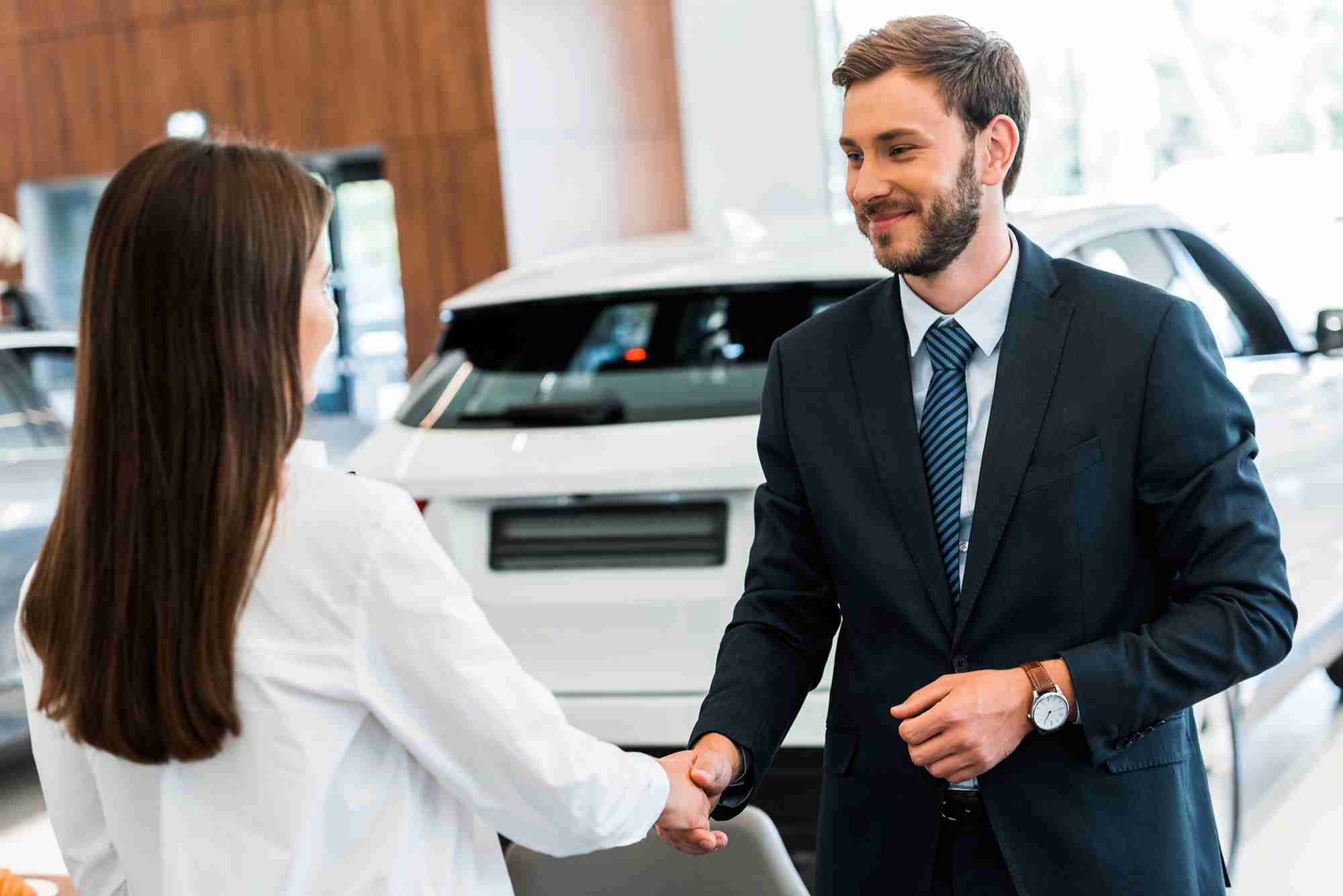 Car salesman shaking hands after a woman buys car