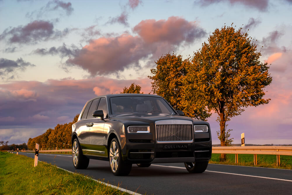 Rolls-Royce Cullinan dricing down an empty road during Autumn