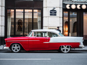 red classic car parked outside of a city building