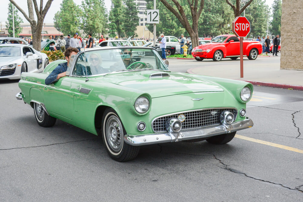 Pistachio green classic car driving in a small town during a car show