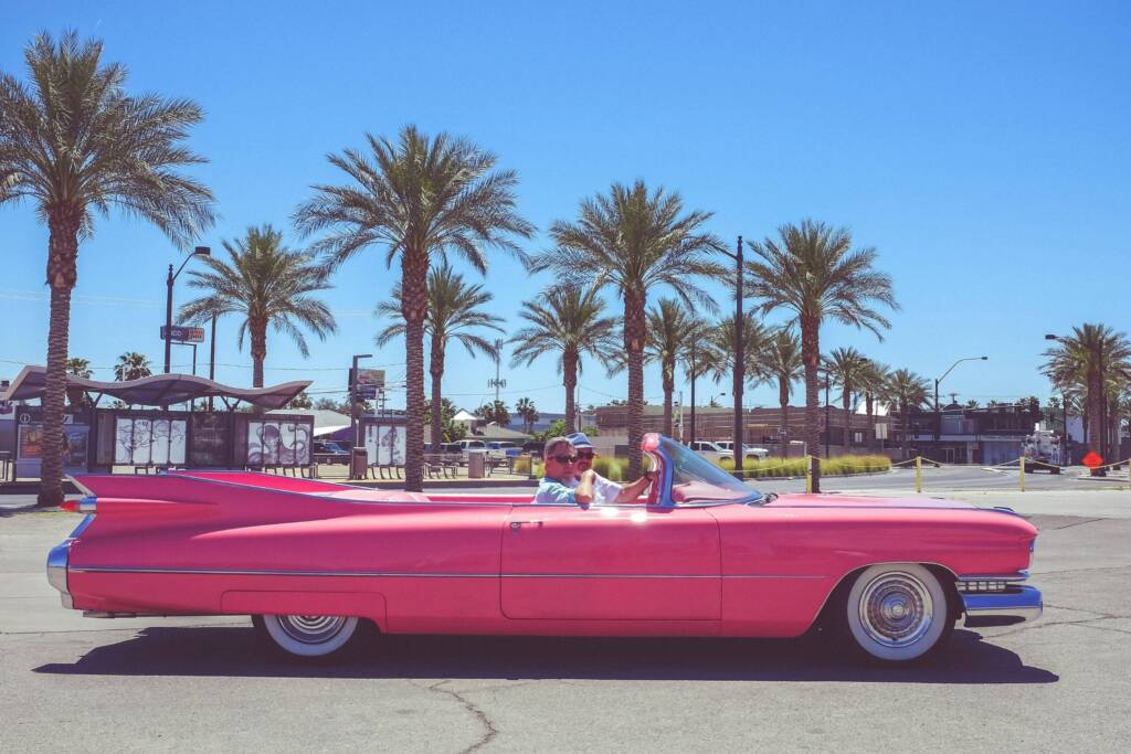 Two men riding in a classic pink convertible