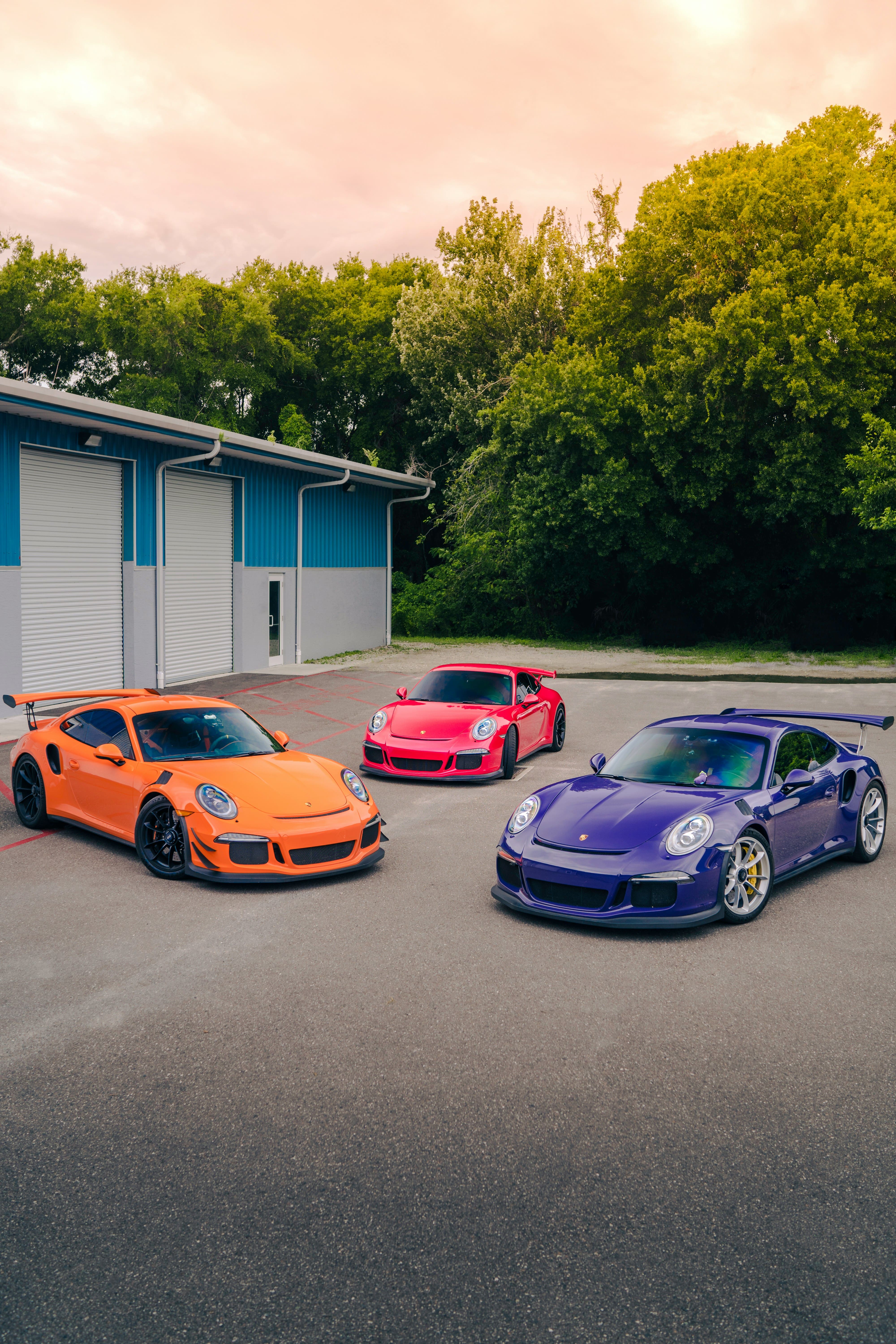 Three Porsche models outside of a garage