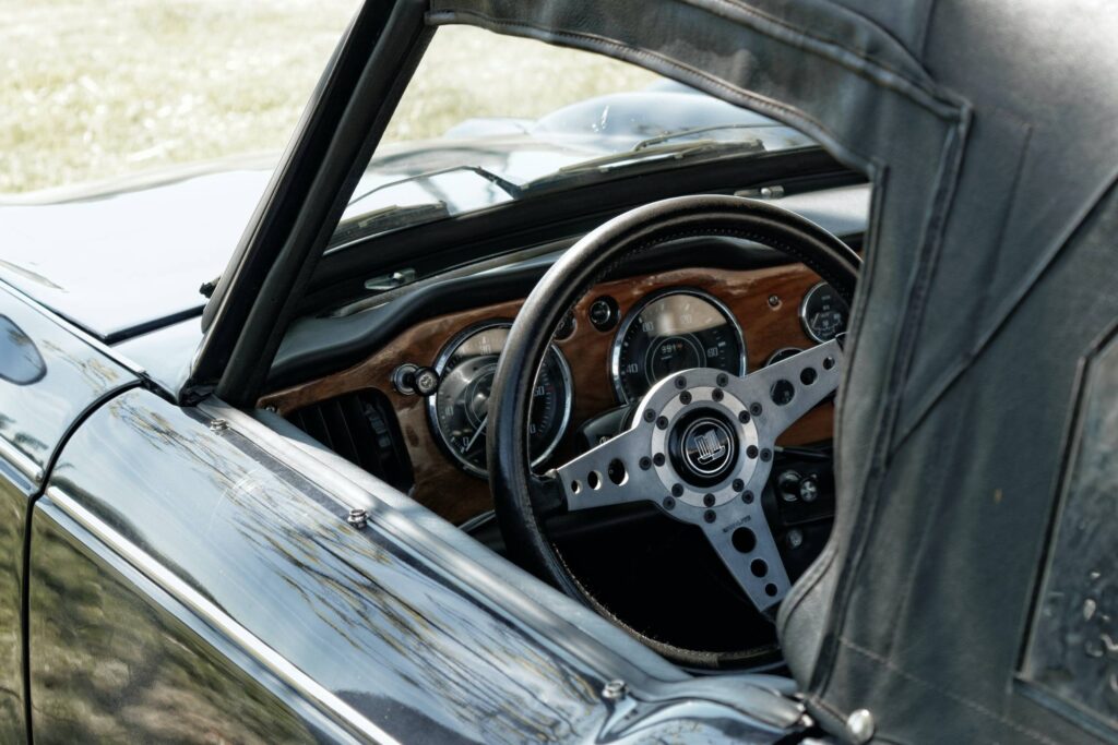 Inside of a classic car with a view of an old steering wheel