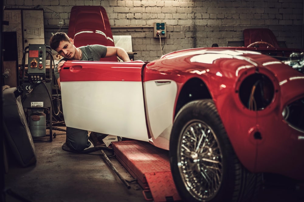 Man inspecting the paint and bodywork of a classic coachbody car