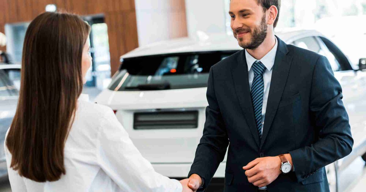 Car salesman shaking hands after a woman buys car
