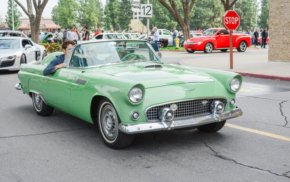 Pistachio green classic car driving in a small town during a car show