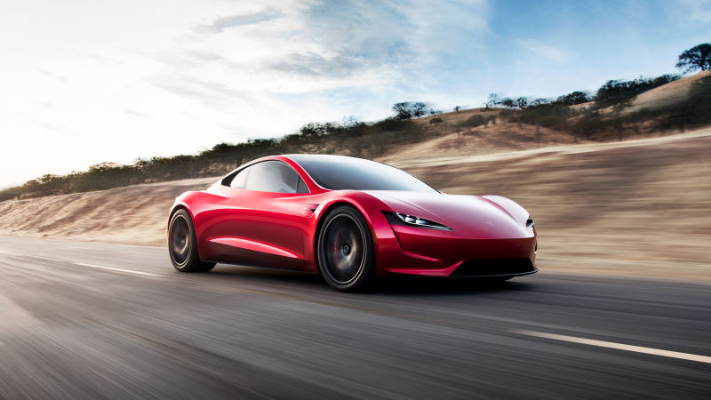 red tesla roadster on winding roads